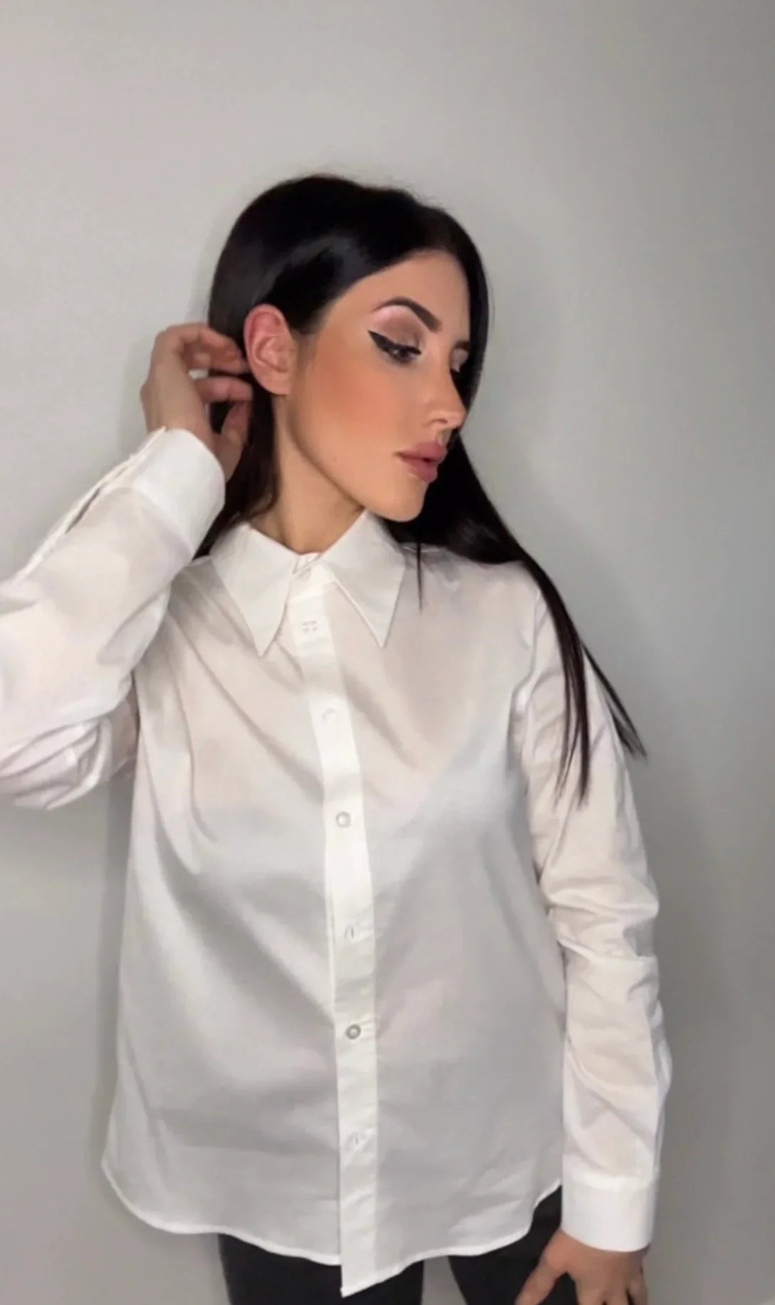 Donna con camicia bianca elegante e sfondo neutro, moda femminile minimalista